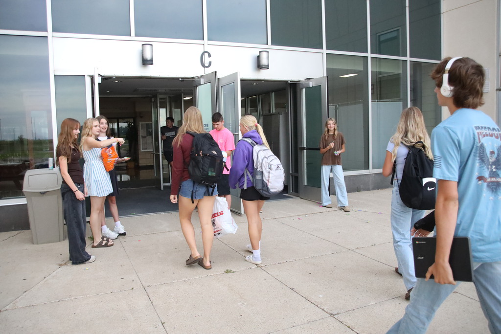 Students walking into the bus doors being greeted by student council members. 