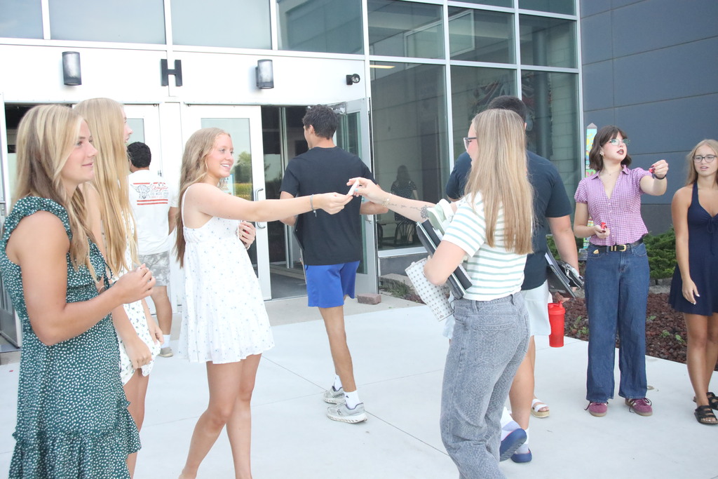 Students walking into the bus doors being greeted by student council members. 