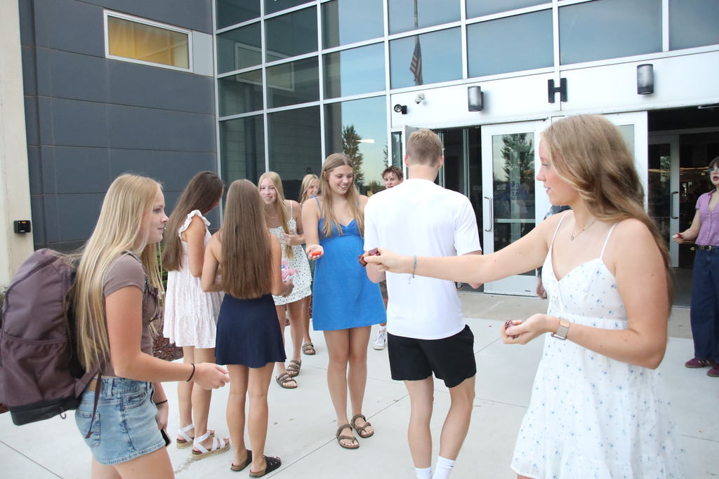 Students walking into the bus doors being greeted by student council members. 