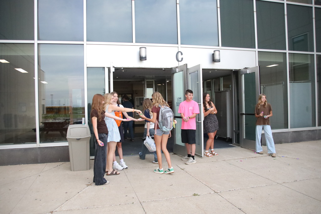 Students walking into the bus doors being greeted by student council members. 