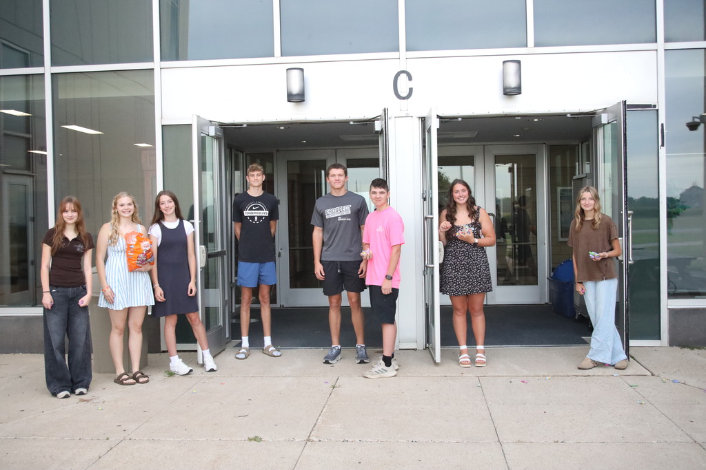 Students walking into the bus doors being greeted by student council members. 
