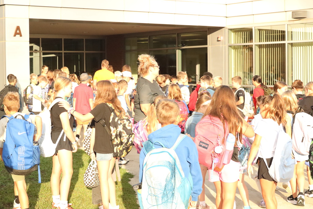students lit up by bright sunlight facing the school building ready for the day.