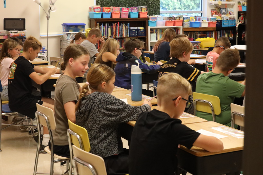 students sitting at desks, looking down, working on work. 