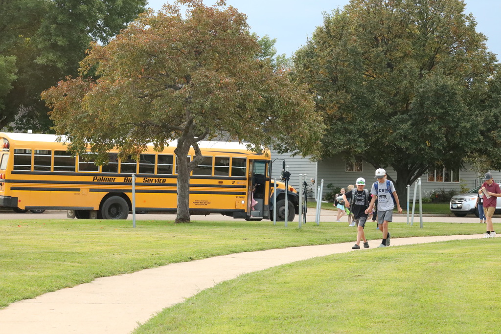 students walking from the bus up a sidewalk. 