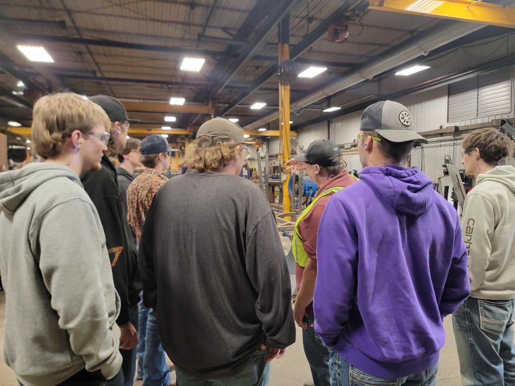 Students standing in manufacturing plant listening to speakers