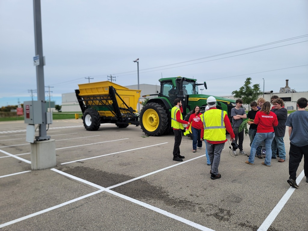 students standing in parking lot looking at heavy equipment.