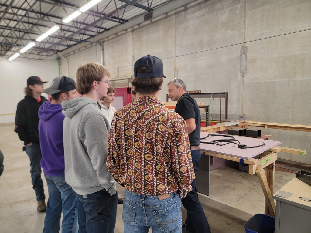 Students standing in manufacturing plant listening to speakers