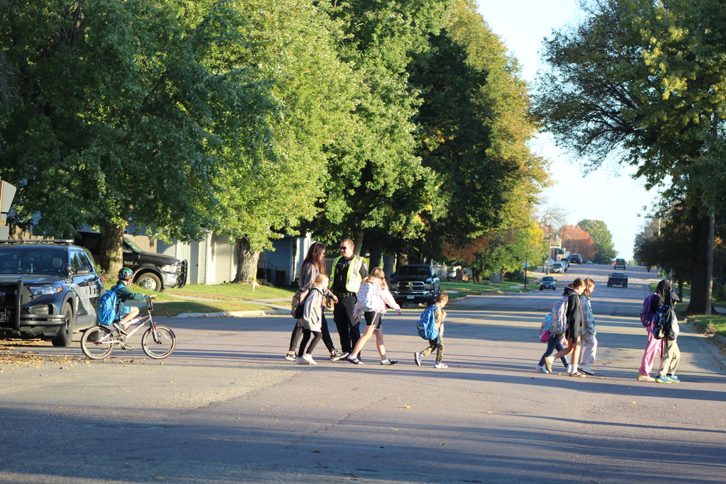 students crossing the street with a police officer stopping traffic.