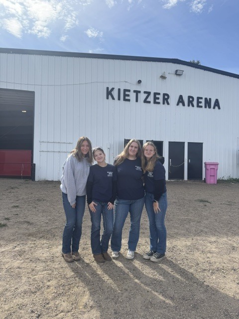four students standing in front of the arena looking at eachother.