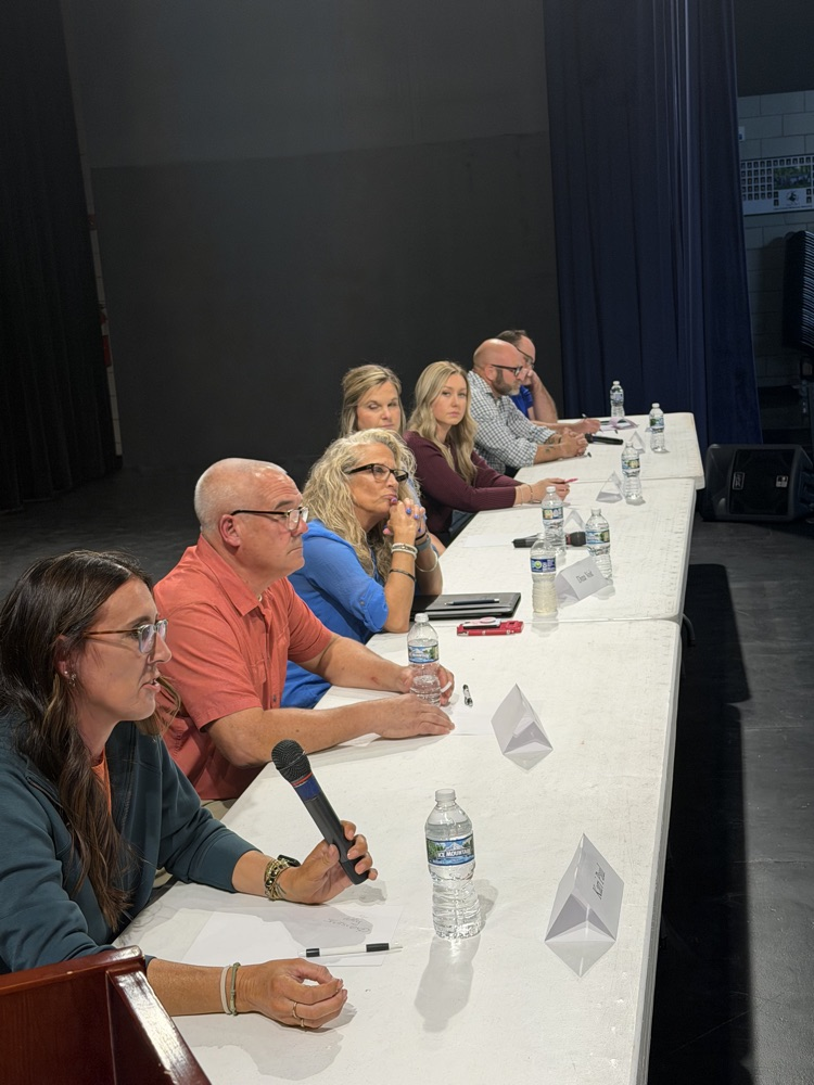 school board candidates sitting at a table in a line answering questions to the public