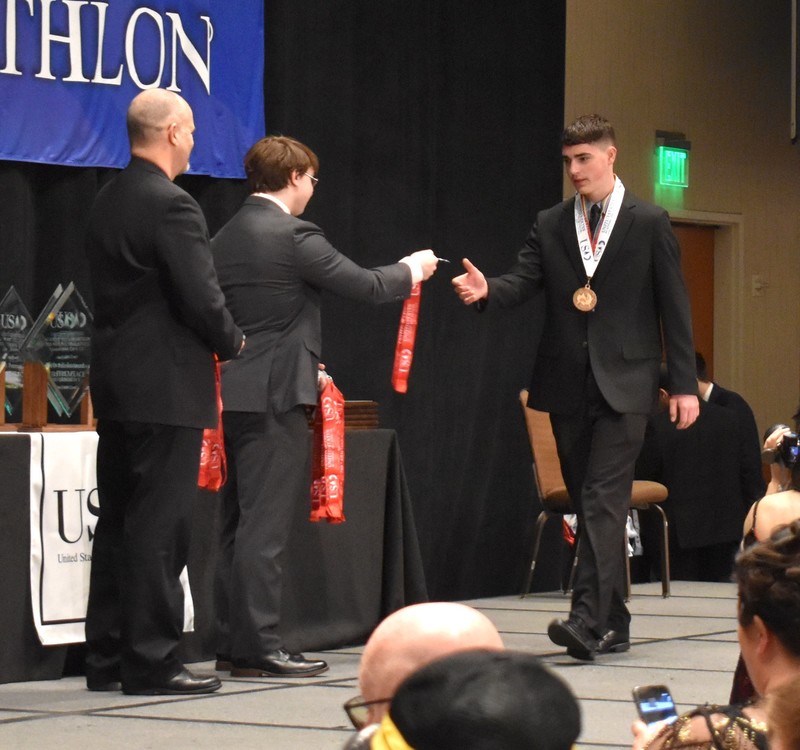 Student receiving medal on staga.