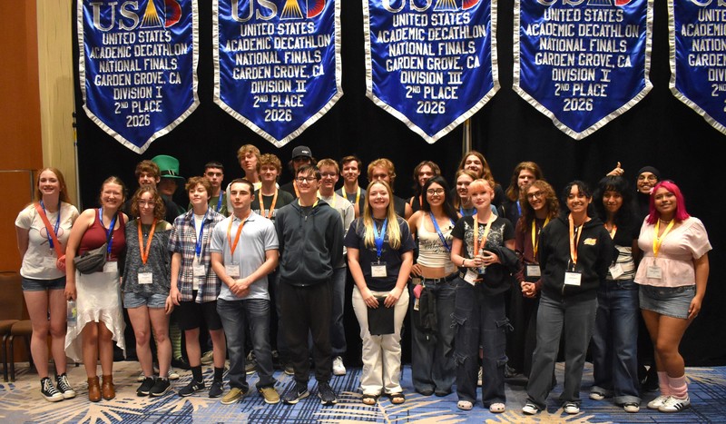 students posing with other students in front of flags.