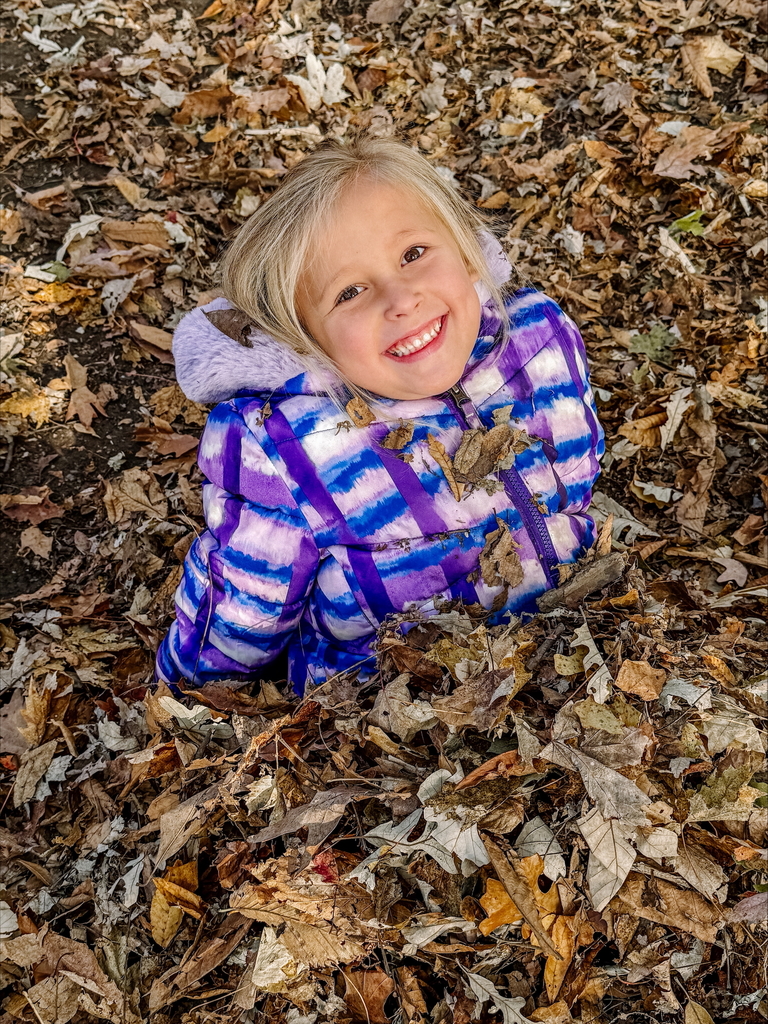 little girl playing in leaves