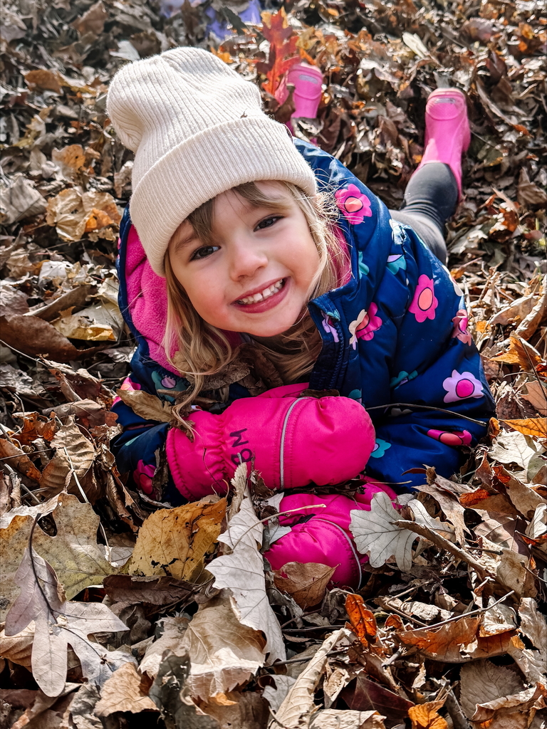 little girl playing in leaves