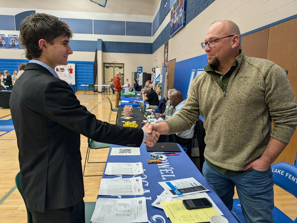 student shaking a man's hand at a job fair