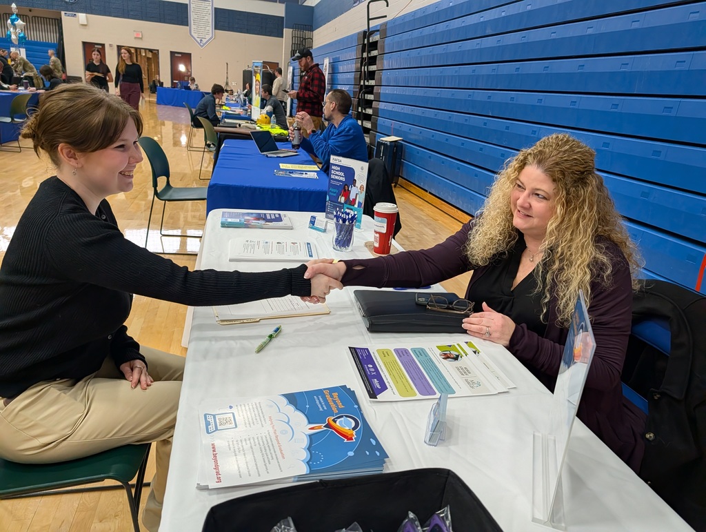 student shaking hands with a woman at a job fair