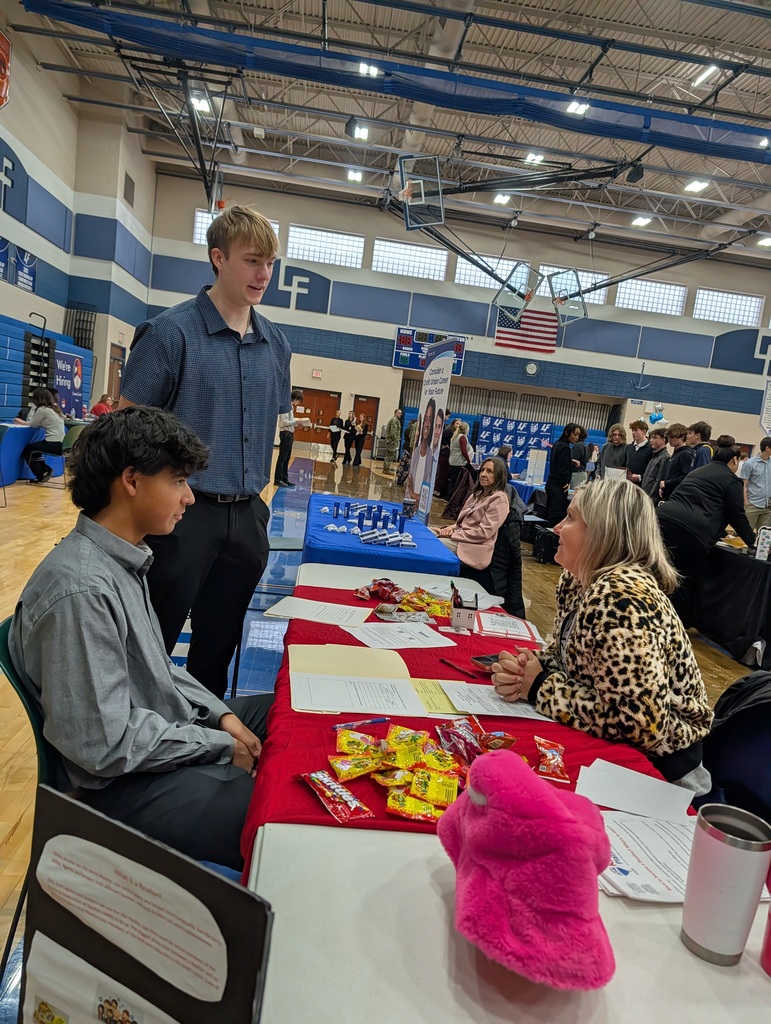 2 students talking to a woman at a job fair