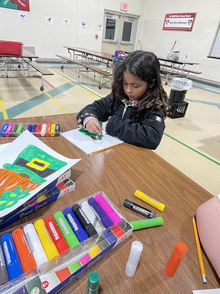 girl drawing at a table full of markers