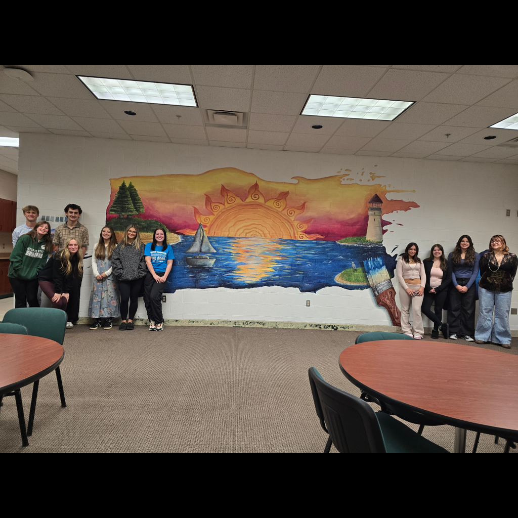 high school students standing in front of  mural of a sunset on a lake with boats