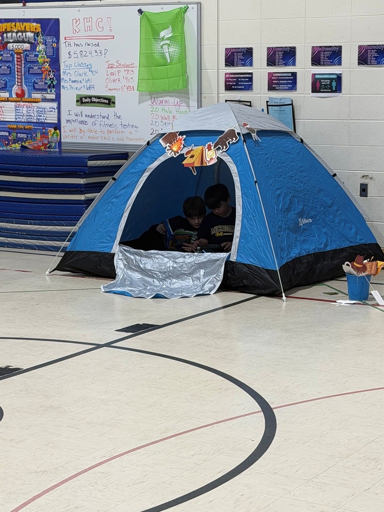 2 children reading in a tent in a gym