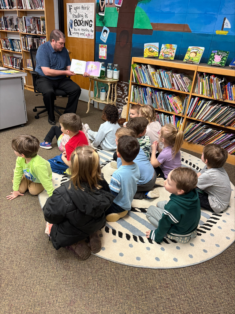 man reading to preschool students in a library