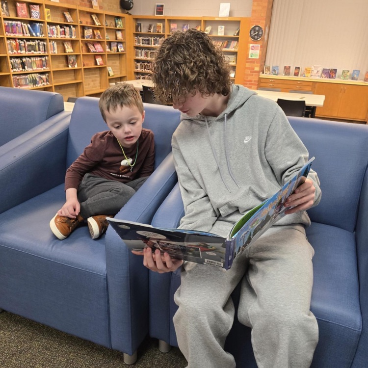 middle school boy reading to preschool student