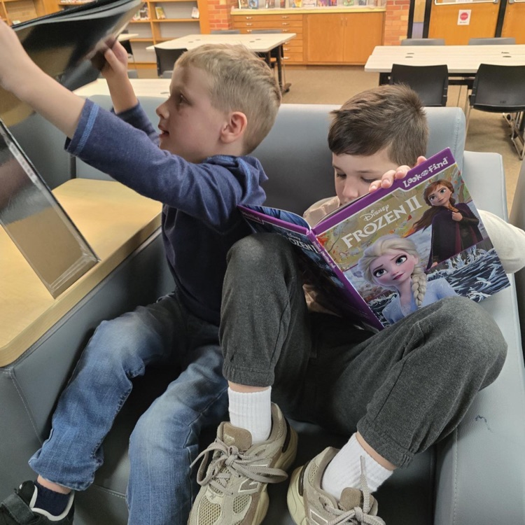 2 boys sitting in a chair holding books