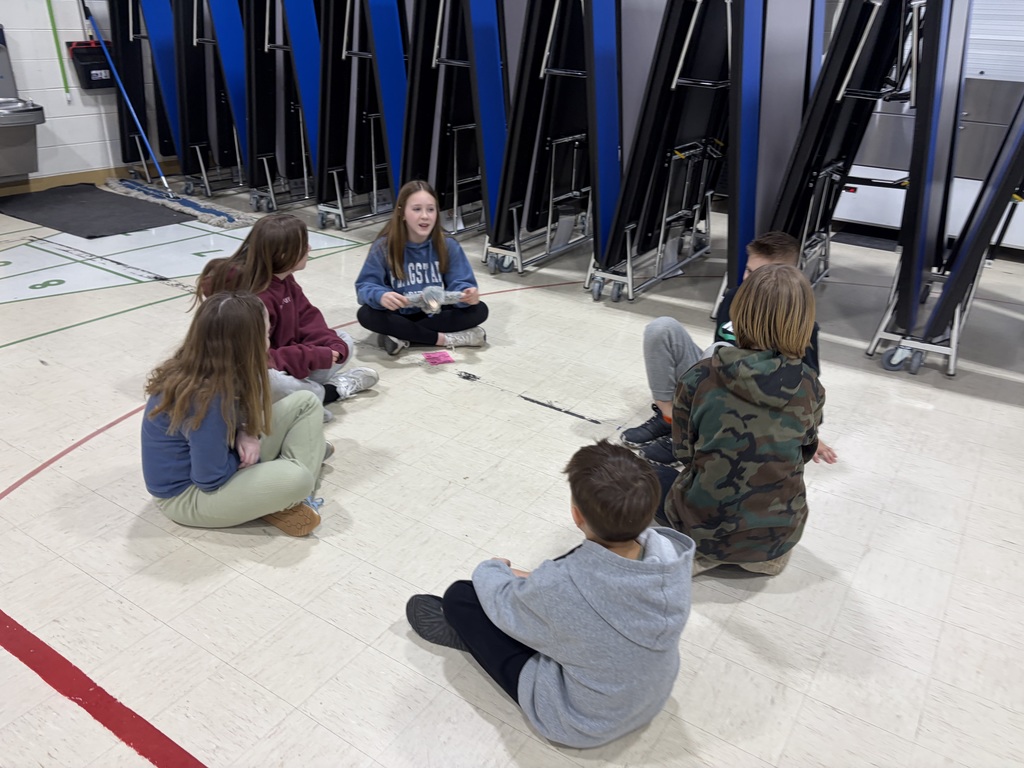 students sitting in a circle in a gym