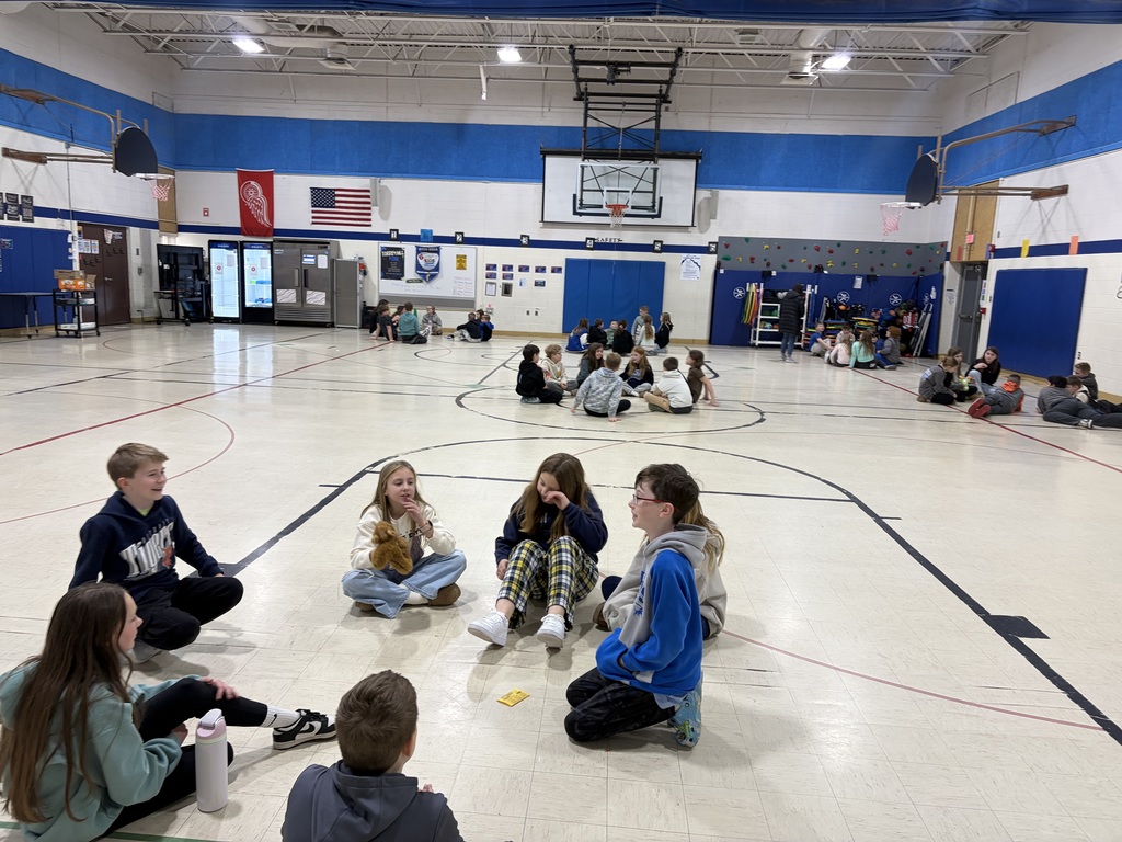 students sitting in a circle in a gym