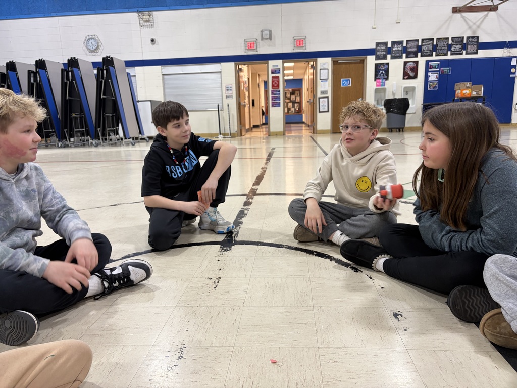 students sitting in a circle in a gym