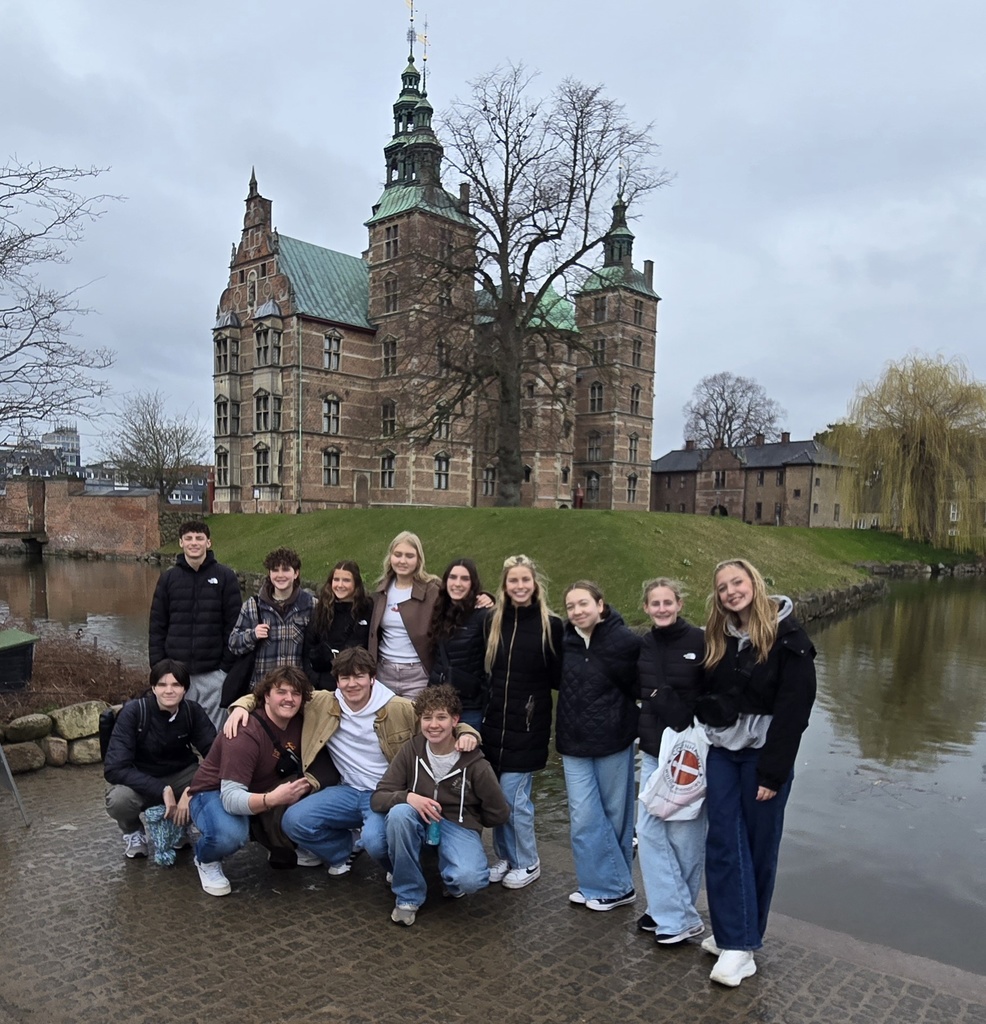 group of students posing in front of a castle