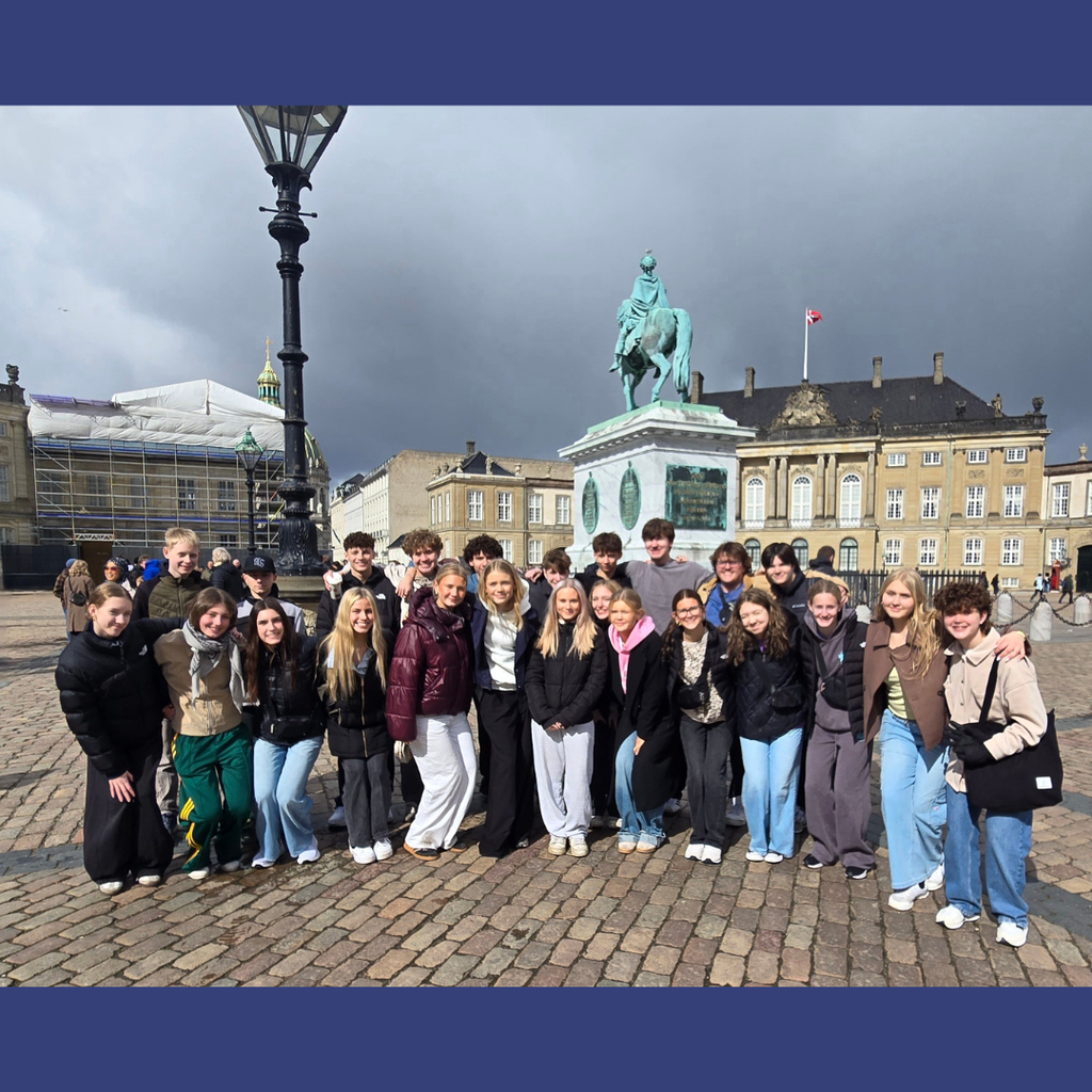 group of students standing in front of a statue