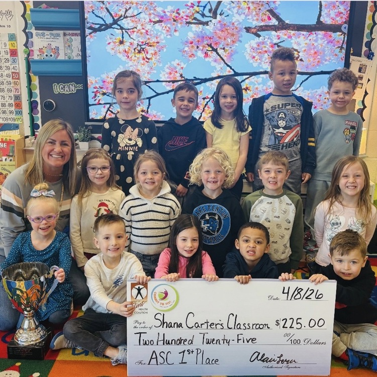 class with a teacher holding a big check and trophy