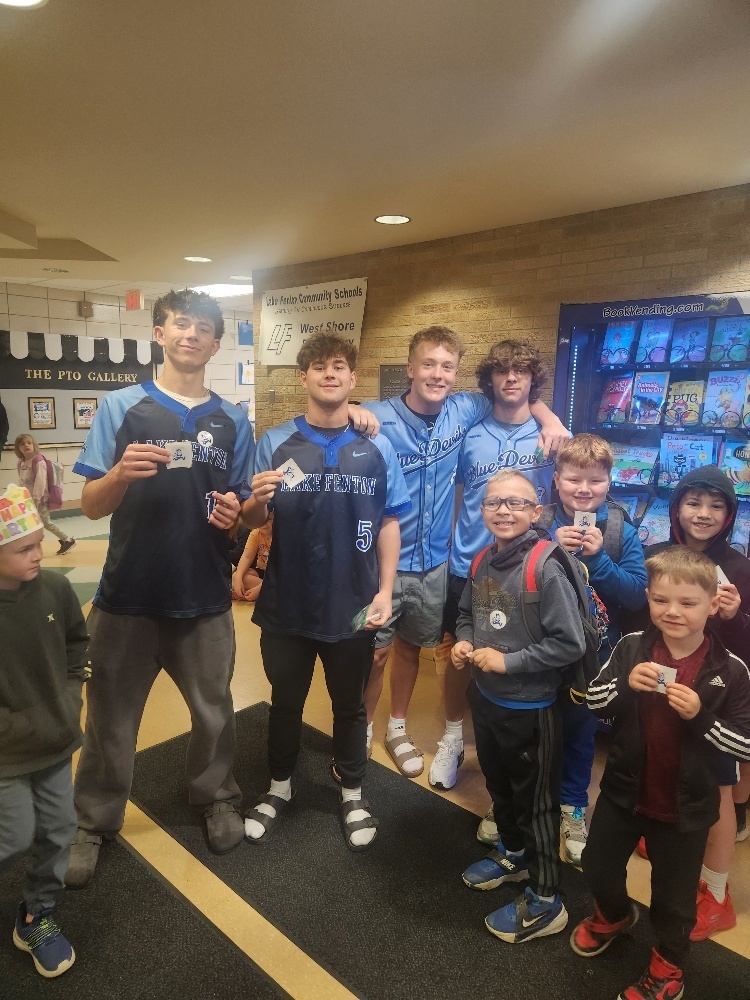 high school baseball players posing with elementary students