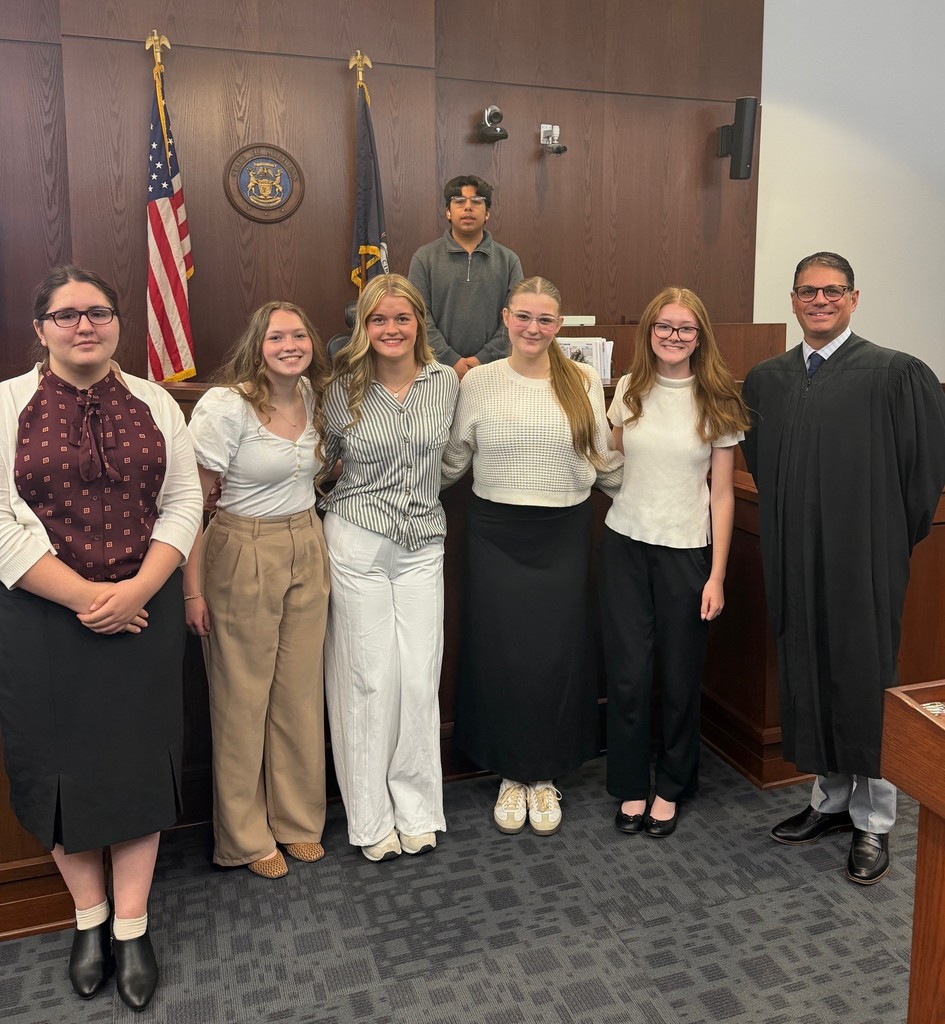 high school students posing in a courtroom with a judge