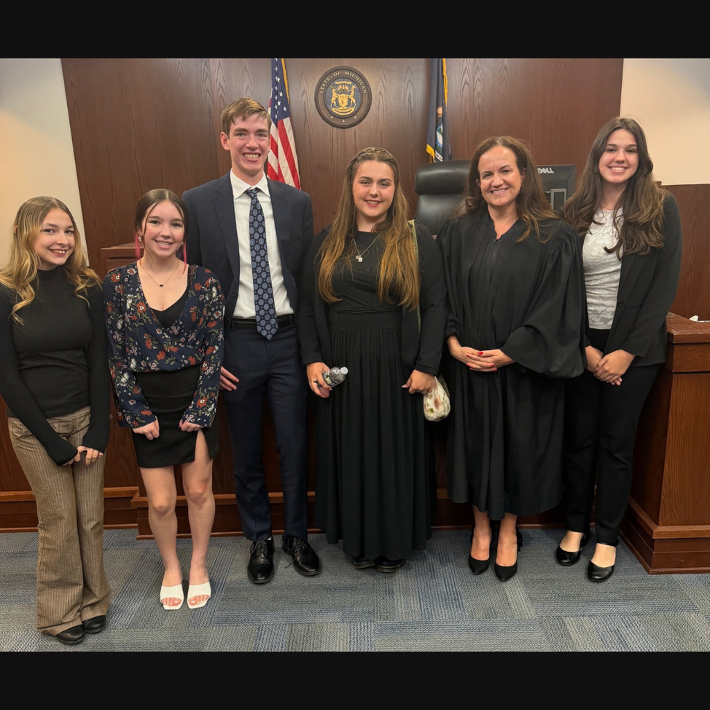 group of high school students posing in a courtroom with a judge