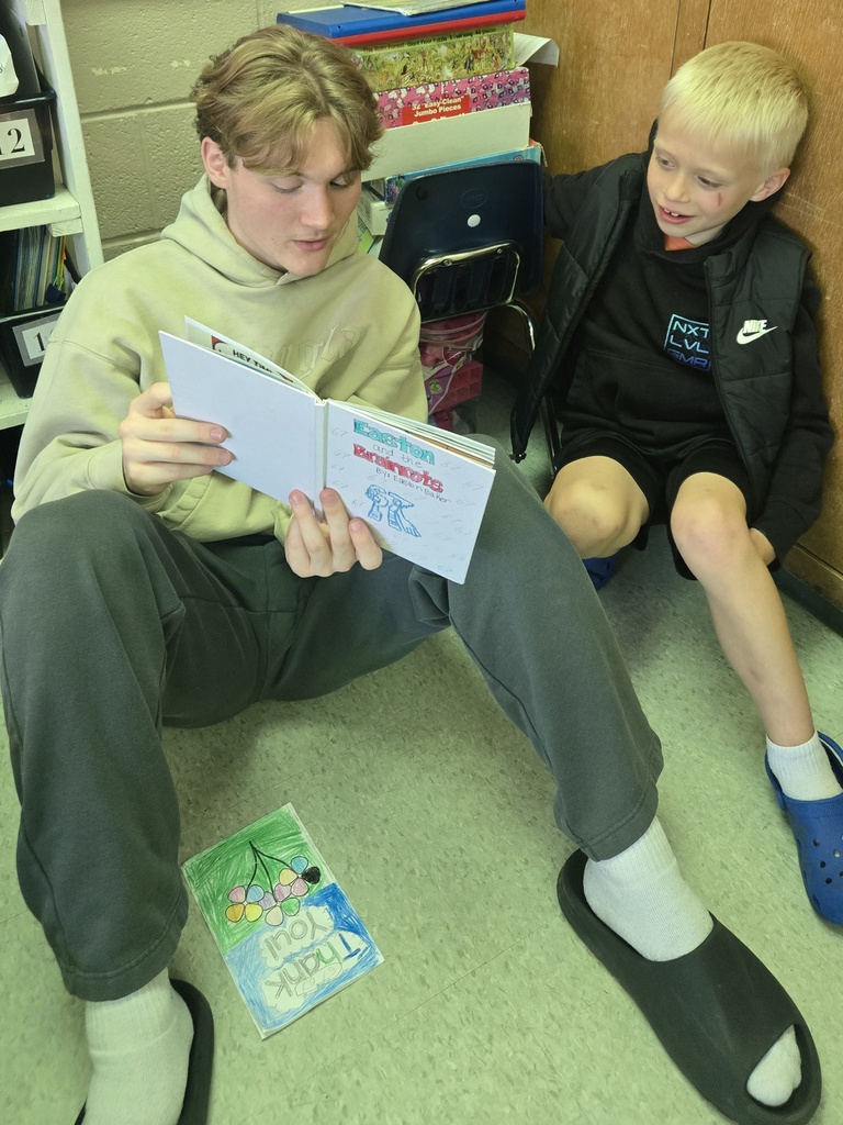 Middle school boy reading a book to a 1st grader