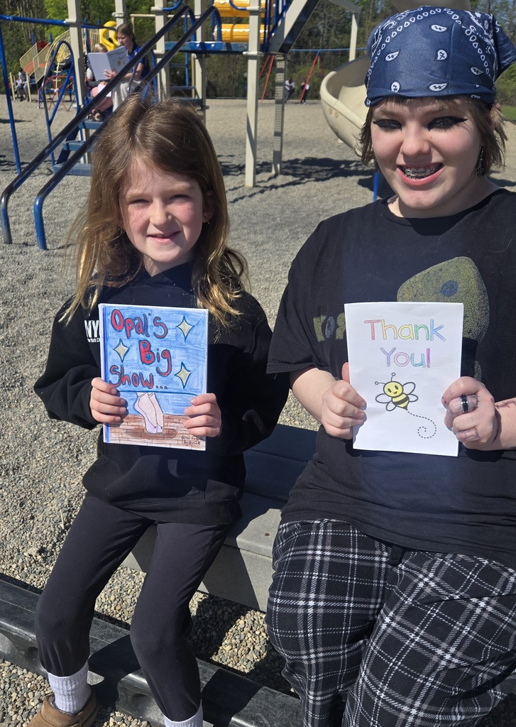 MIddle school girl posing with a first grade girl and each is holding a book