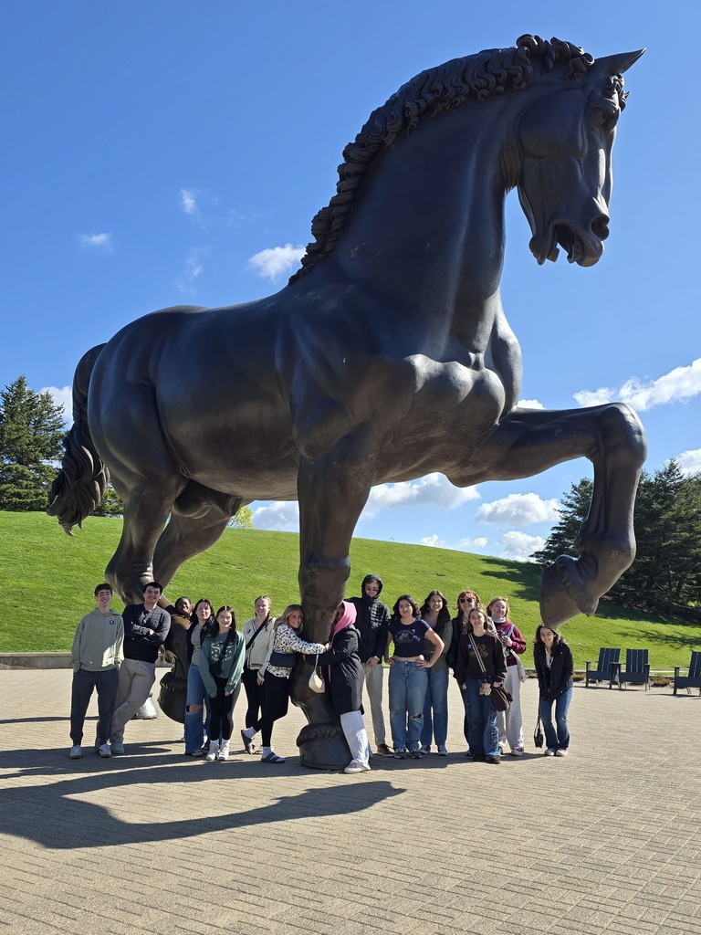students posing in front of giant statue of a horse