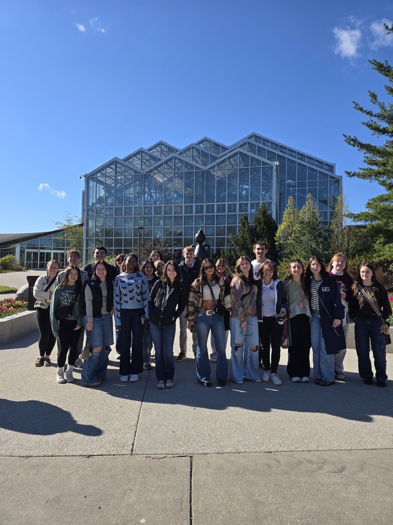 high school students posing in front of a glass building
