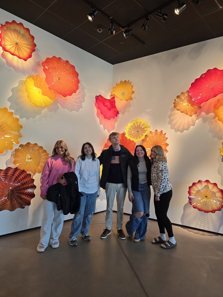 high school students posing in front of glass art work