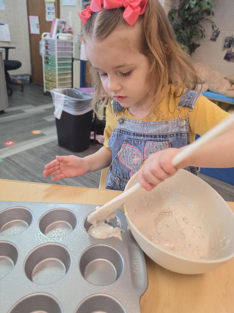 preschool student playing with a spoon and dough