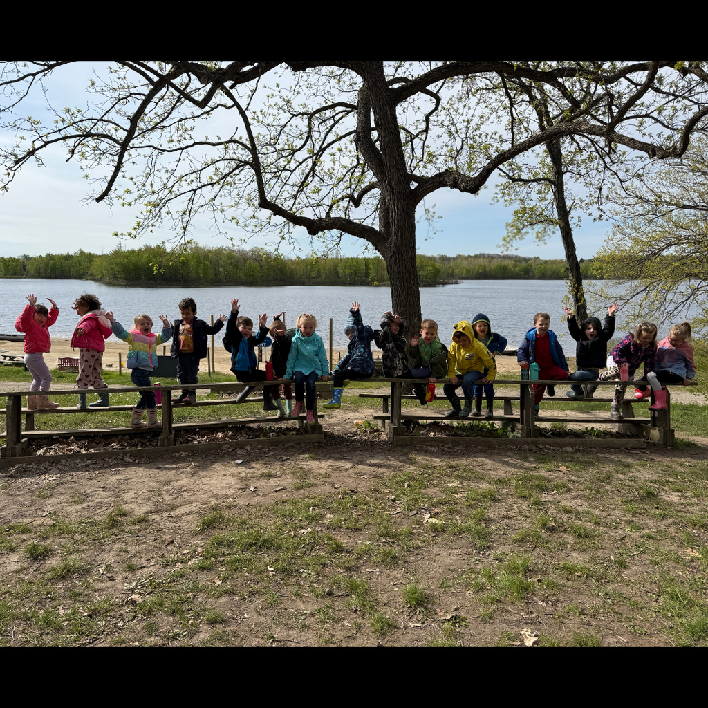 large group of kids posing in front of a lake