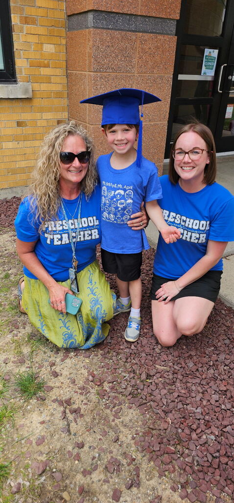 boy posing in blue graduation cap with 2 women