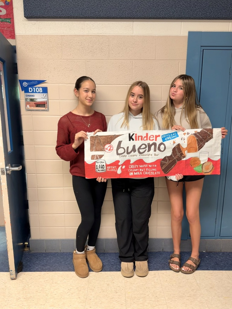 3 girls holding giant drawing of a KinderBueno package