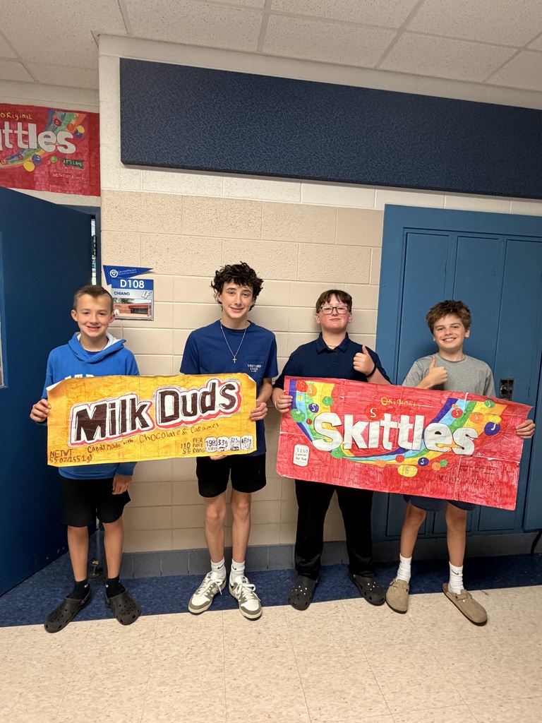 4 boys holding large drawings of Milk Duds and Skittles bags