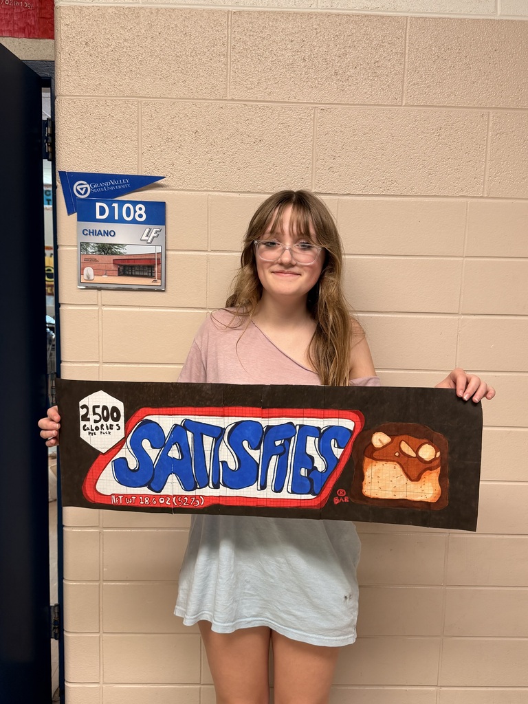 girl holding giant drawing of a snickers wrapper