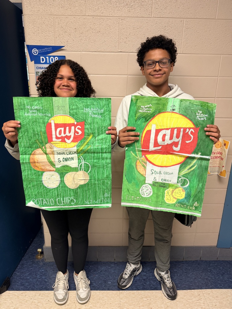 2 students holding giant drawings of Lays Sour Cream & Onion chip bags