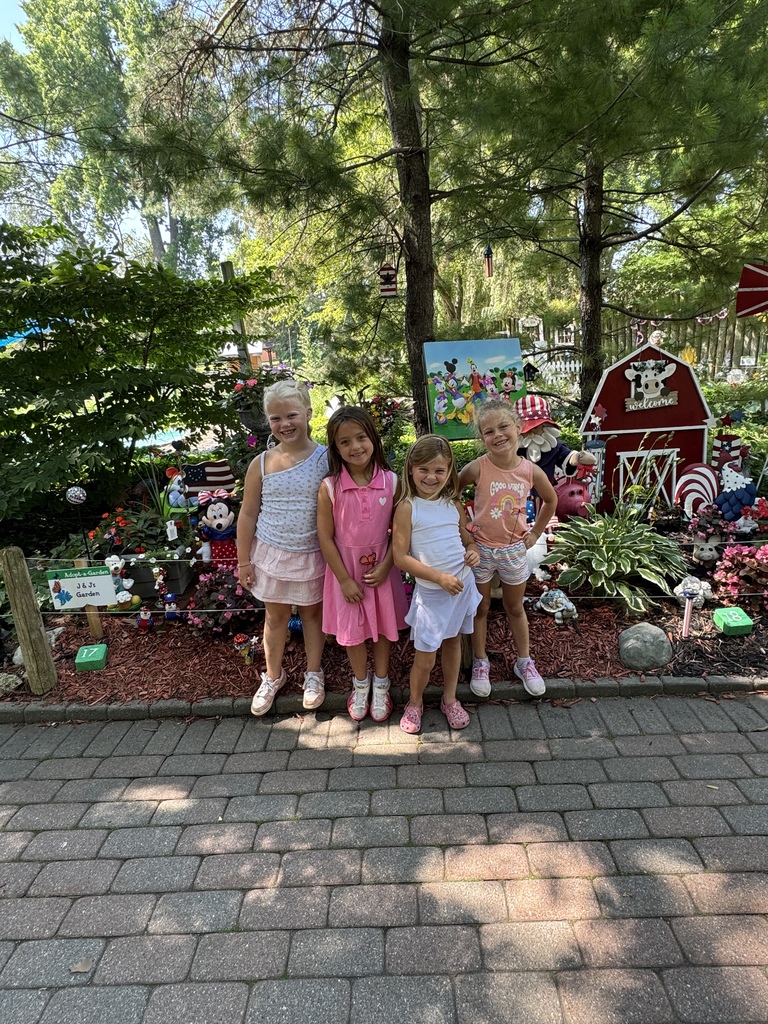 4 girls posing in front of a garden decorated with Disney things