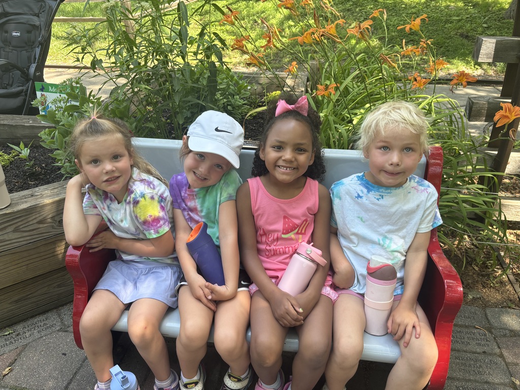 4 girls posing on a bench in front of flowers